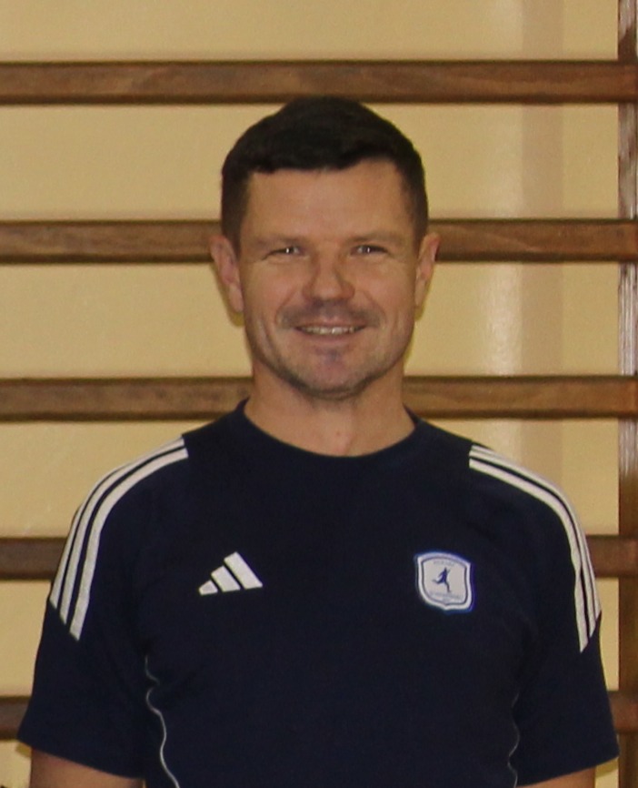 Mężczyzna w ciemnym trykocie z logo adidas i emblematem zespołu